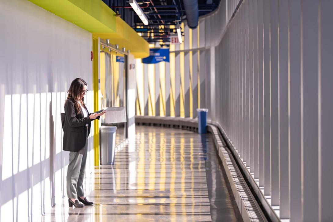 A female student checks her notes while standing in a hallway at NEIU's El Centro campus
