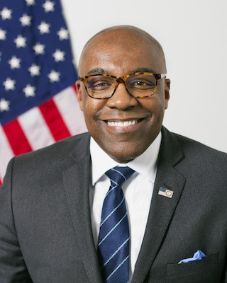 A photo of Illinois Attorney General Kwame Raoul portrait in color with a U.S. flag in the background.