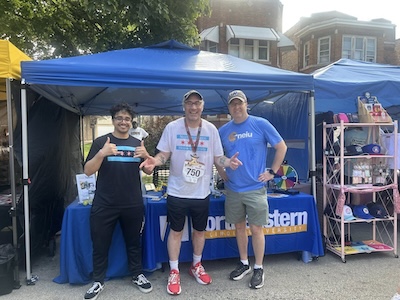 Photo (from left to right): Muhammad Elbadawi, Tim Libretti and Brennen Keefe smiling in front of the Northeastern booth at the Corrida del Mariachi 2025.