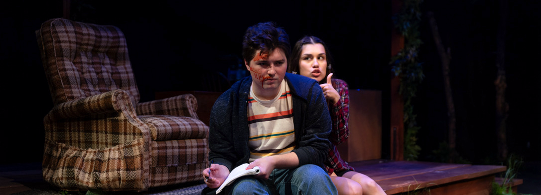 black bear island: an actor with blood on their face sits and writes in their journal with another actor sitting behind them pretending to be a storm trooper