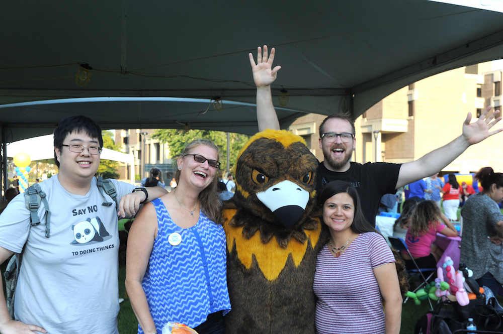 Four Golden Eagle Alumni and Family Picnic attendees pose with Goldie, Northeastern's mascot