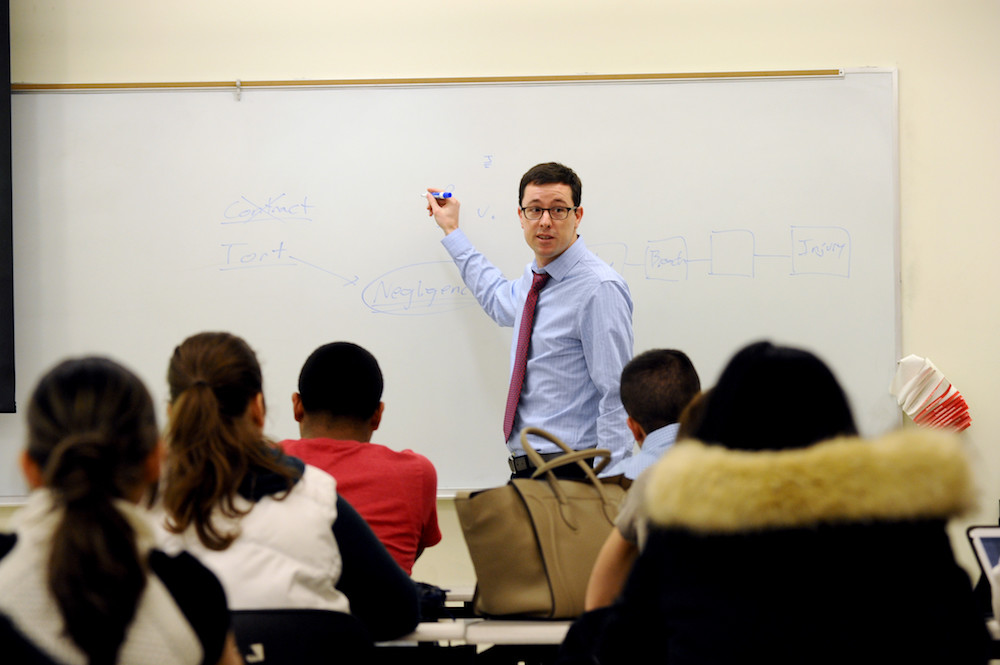 Assistant Professor of Business Law Richard Kilpatrick standing in front of a whiteboard in a classroom of students