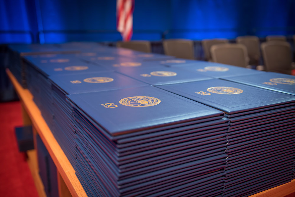 Stacks of diploma covers sitting on a table at a Commencement ceremony