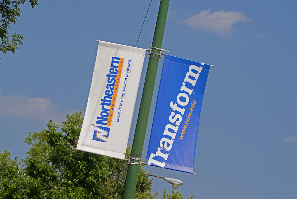 Two light pole banners that bear the University name and the word Transform
