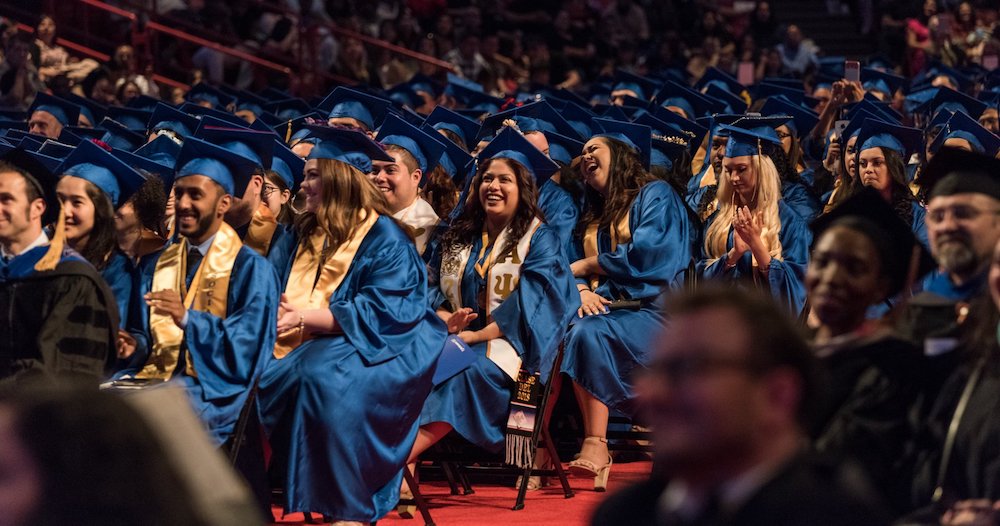 Graduates dressed in blue robes seated at a Commencement ceremony