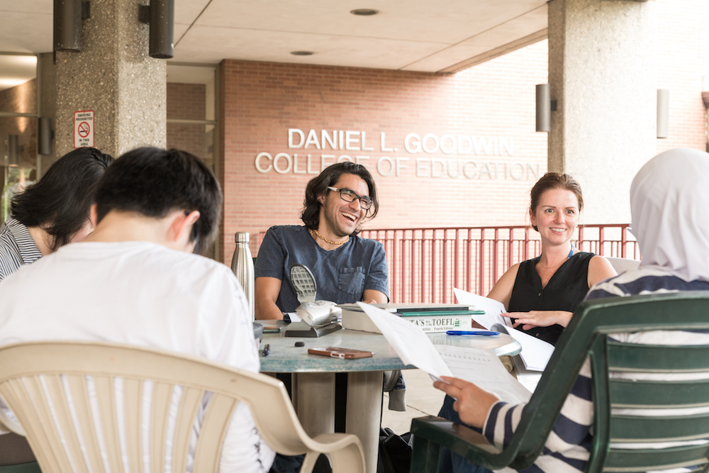 Five students sit around a table on the outdoor patio of Lech Walesa Hall