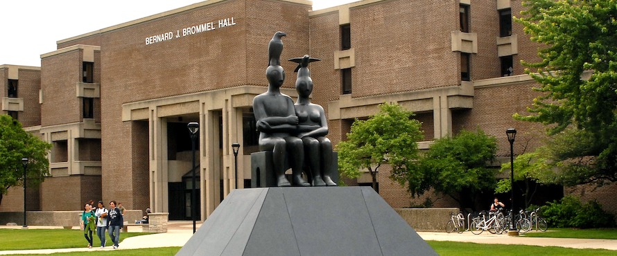 A statue is shown in front of a brick building on Northeastern's campus