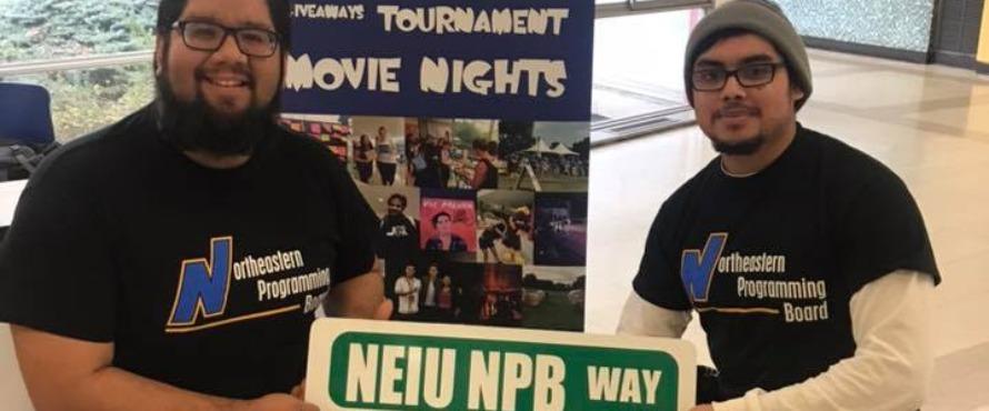 Two members of Northeastern's Programming Board hold a mock street sign reading "NEIU NPB Way"