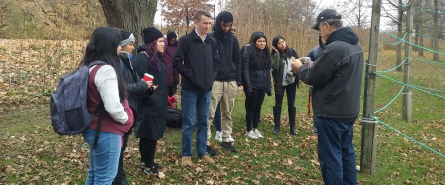 Dan Creely (right) teaches eight students while standing under a tree.
