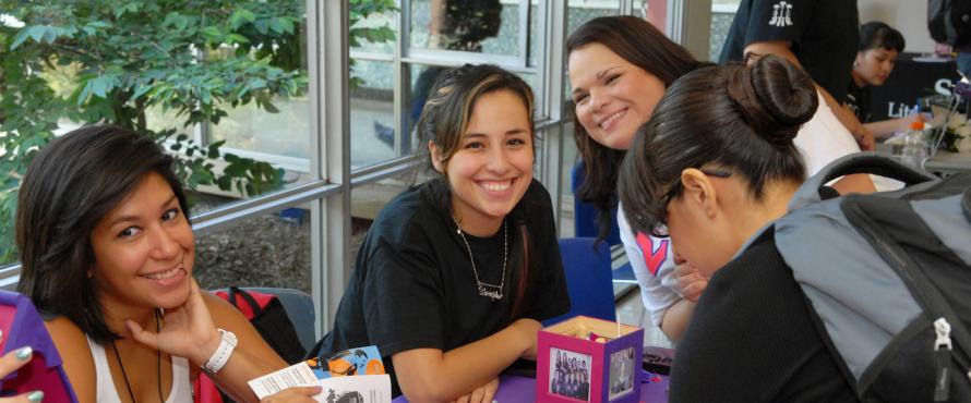Three women smiling at a Greek Life tabling event in Village Square