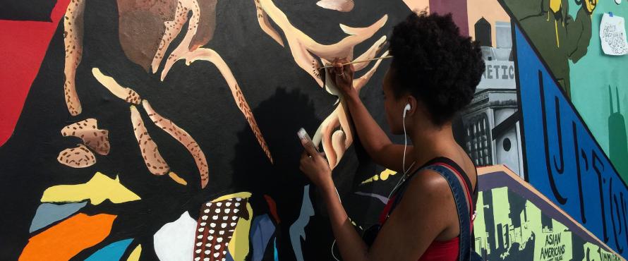 female student painting a colorful mural