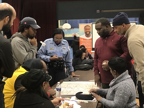 Troy Harden with David Rivers and Englewood residents at a community meeting discussing research over a map of the community