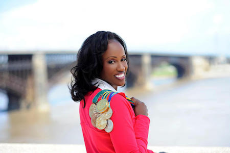 Olympic medalist Jackie Joyner-Kersee looks back over her shoulder, over which are her Olympic medals